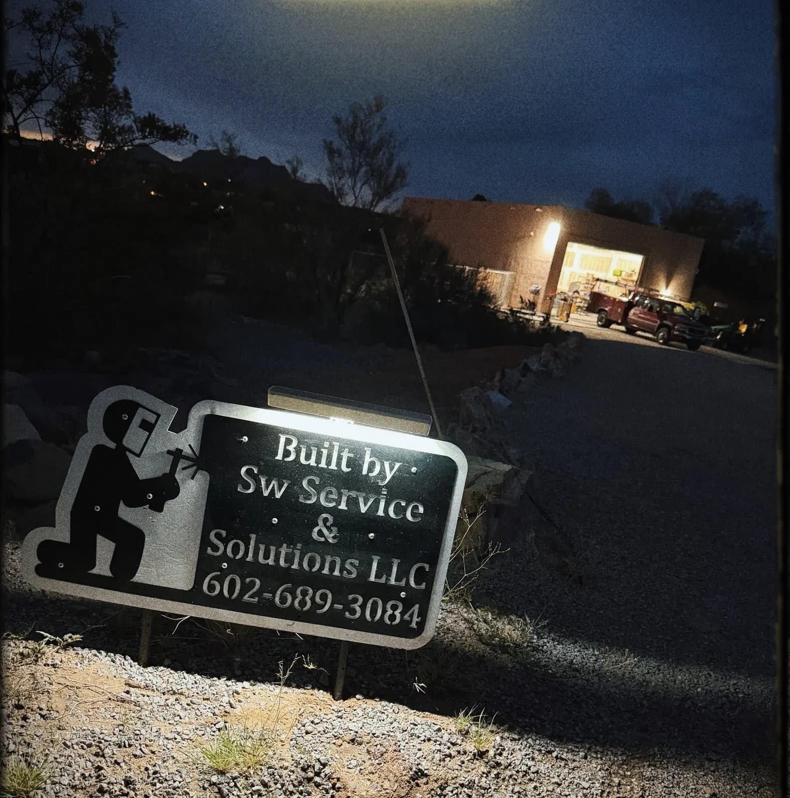 Plasma-cut steel 'Built by SW Service & Solutions LLC' yard sign lit at night
