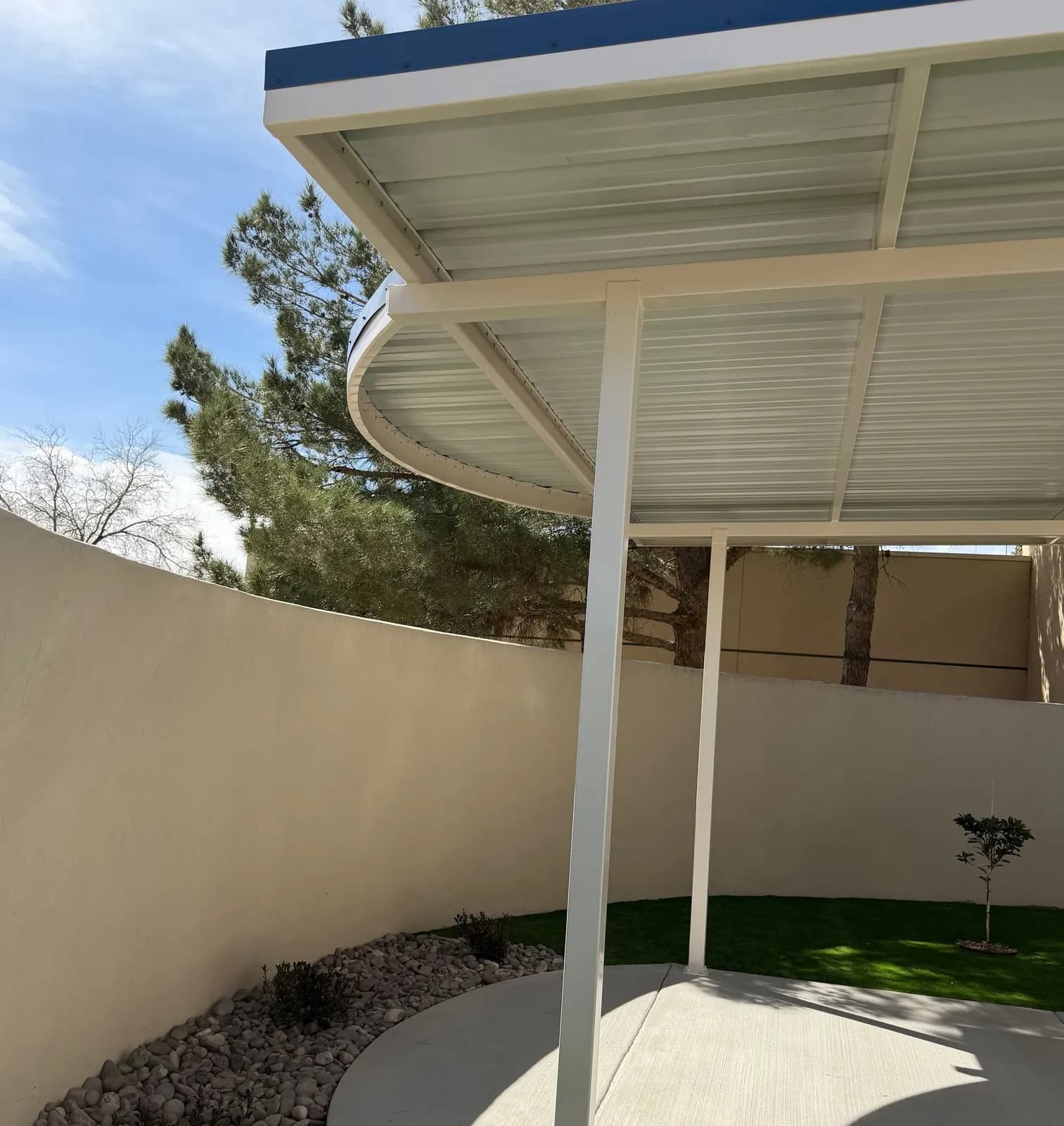 Underside of a curved steel shade canopy showing the welded frame and posts