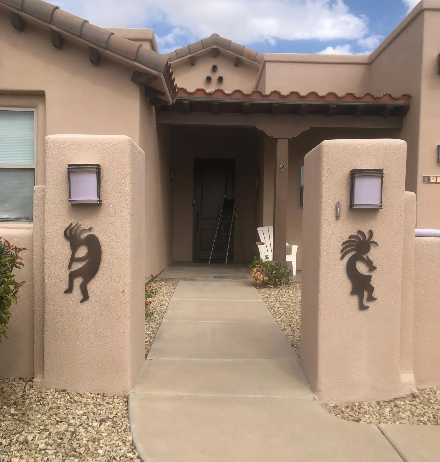 Plasma-cut Kokopelli metal art mounted on stucco entry pillars