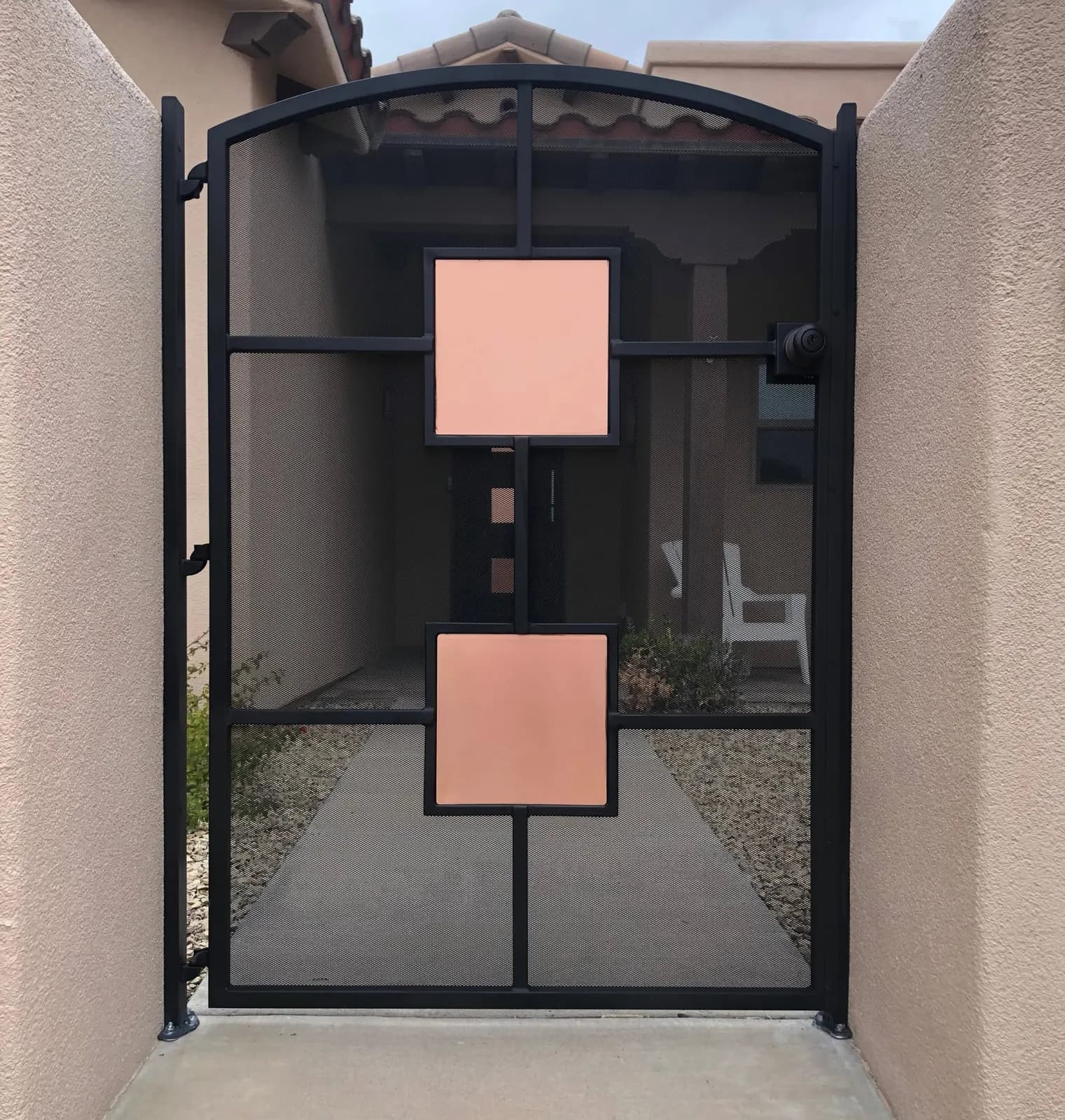 Modern black steel courtyard gate with copper-finish square panels