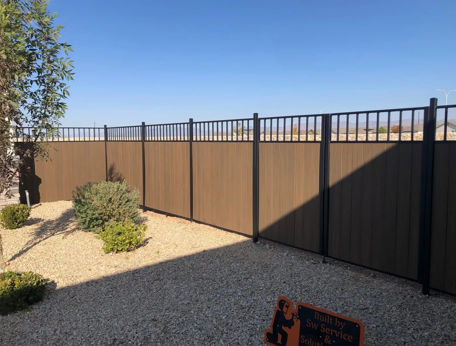Composite privacy fence in a black steel frame with a picket view rail