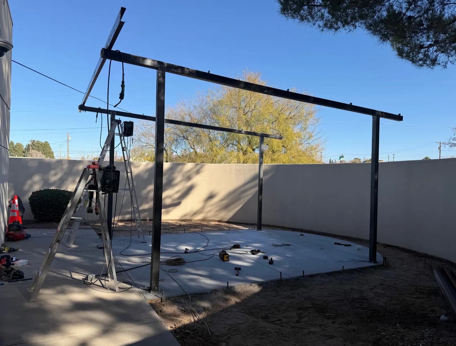 Welded steel canopy frame going up on a new concrete pad during installation