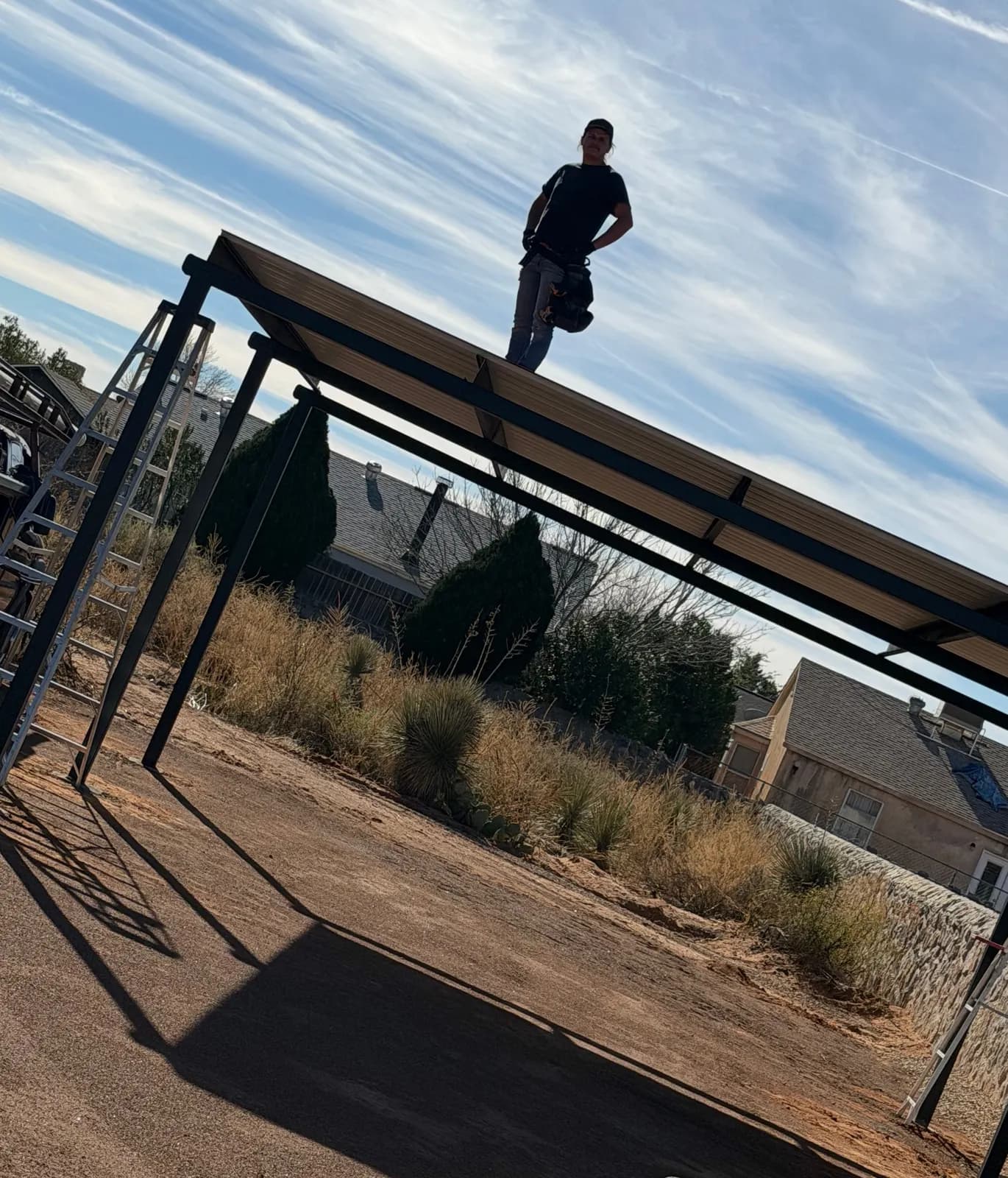 Crew member on top of a steel carport frame during installation