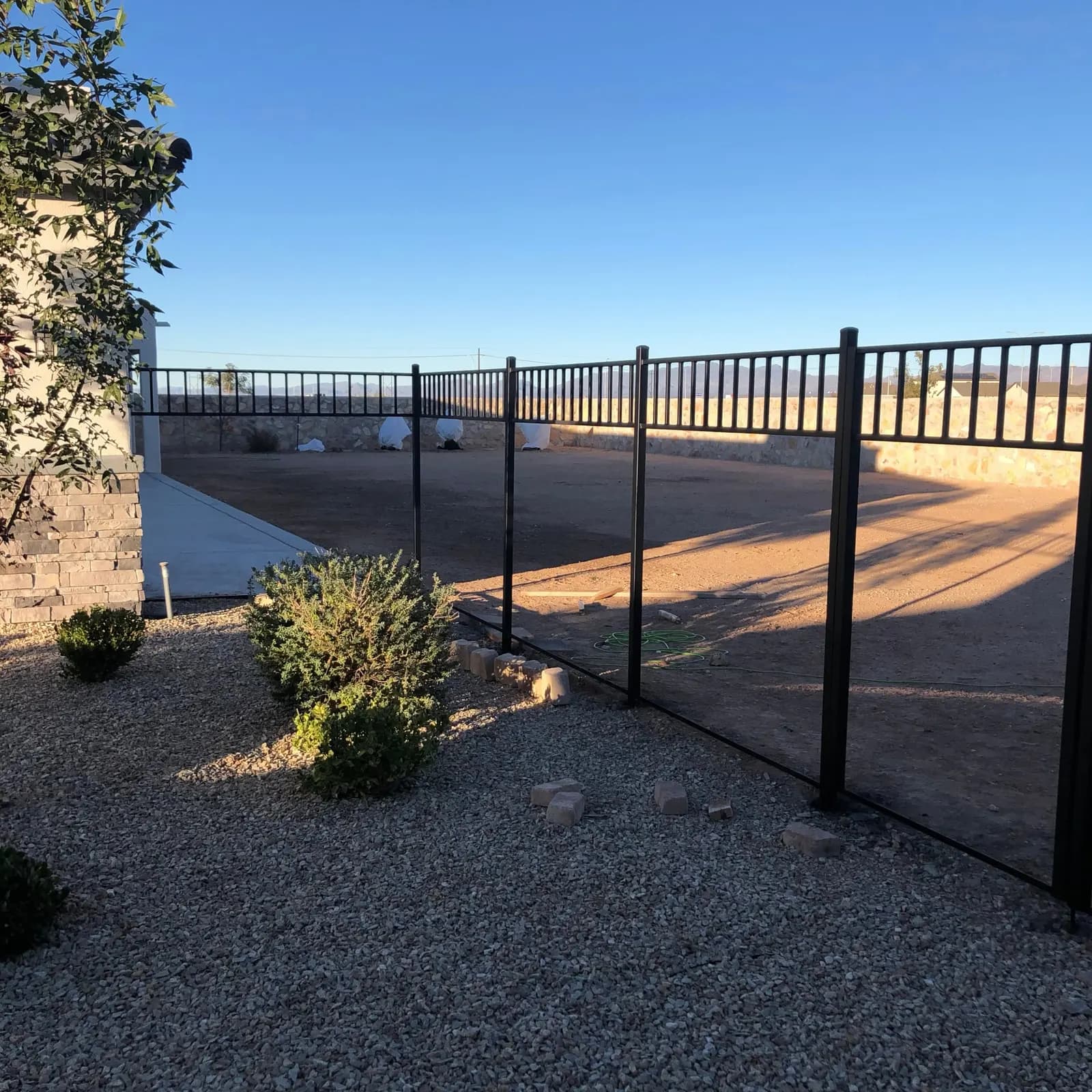 Black steel view fence running along a desert backyard