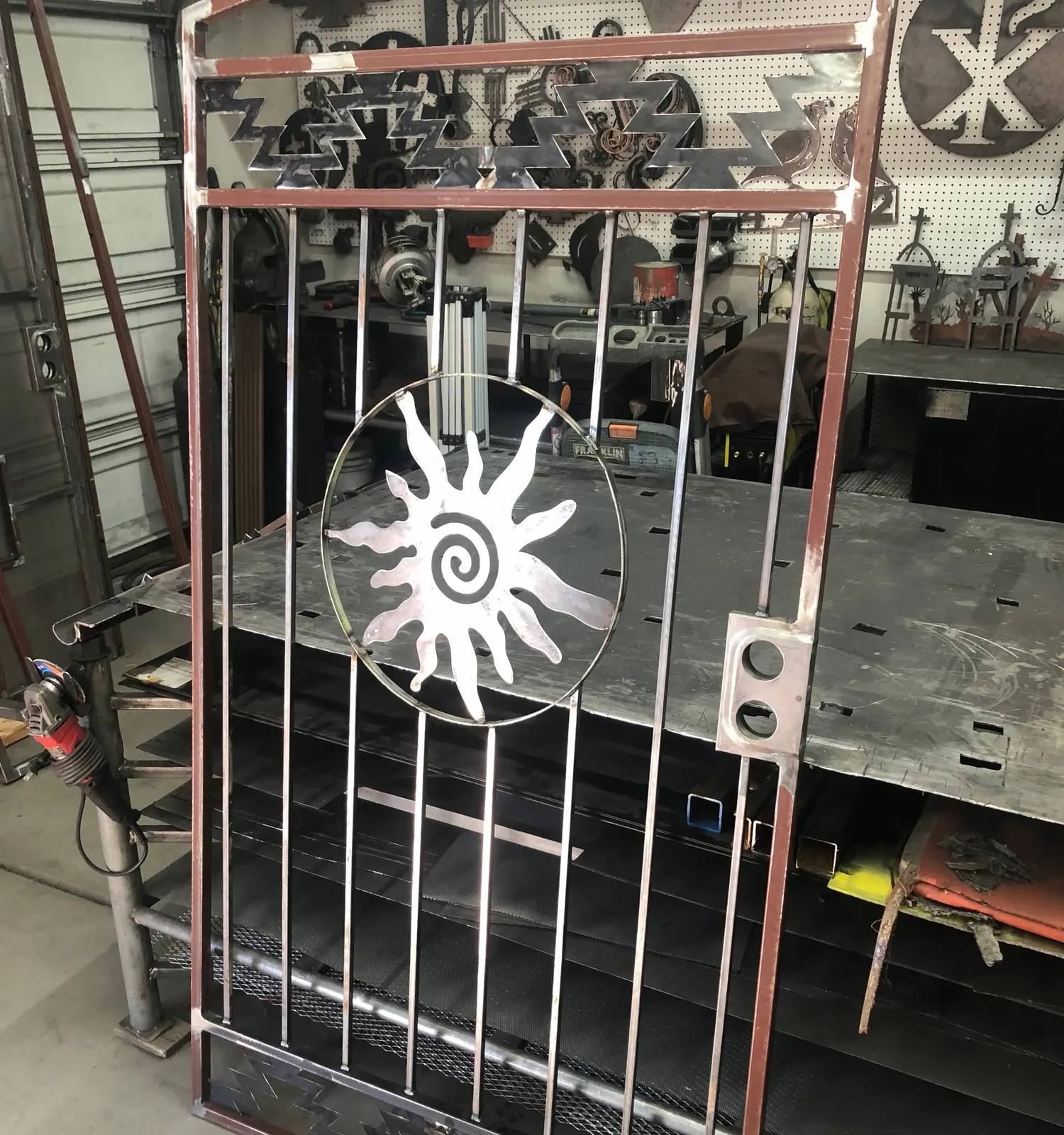 Courtyard gate with a spiral-sun medallion during fabrication in the welding shop