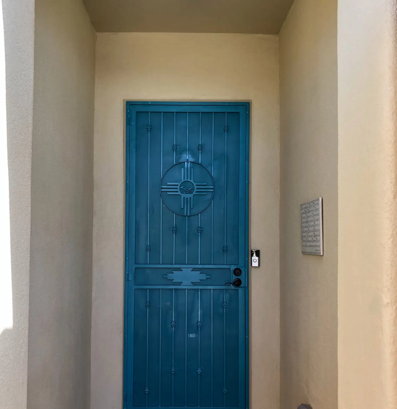 Turquoise Zia security door at a recessed stucco entry, Las Cruces