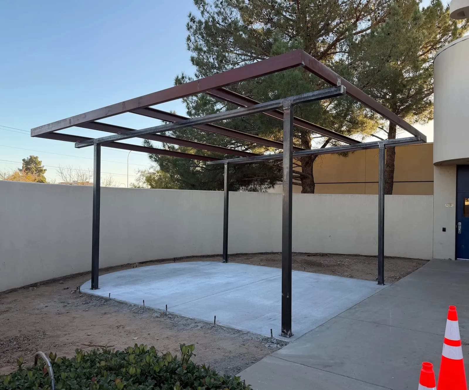 Welded steel canopy frame and purlins set on a fresh concrete pad before roofing