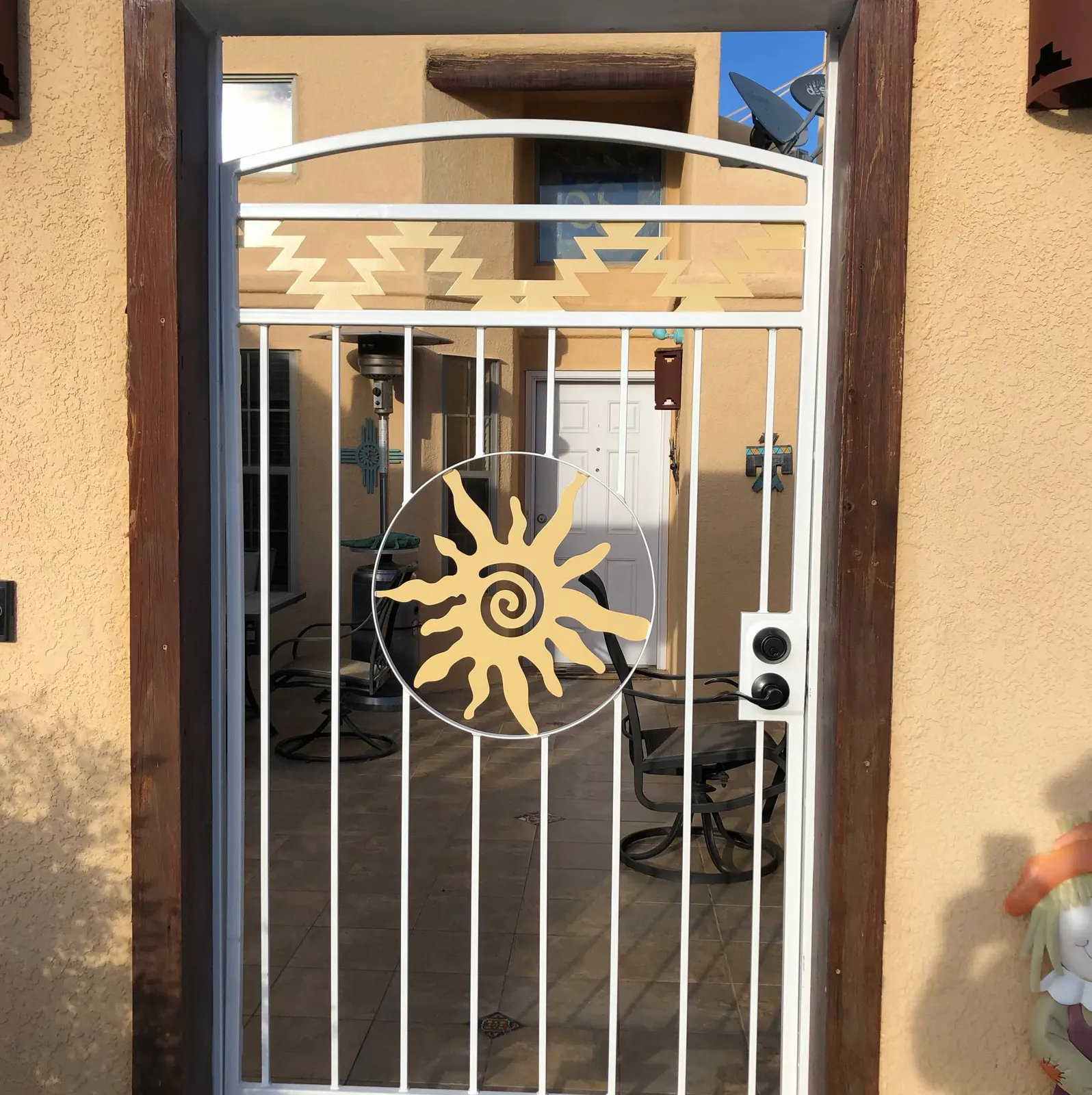 White steel courtyard gate with a gold spiral-sun cutout, Las Cruces