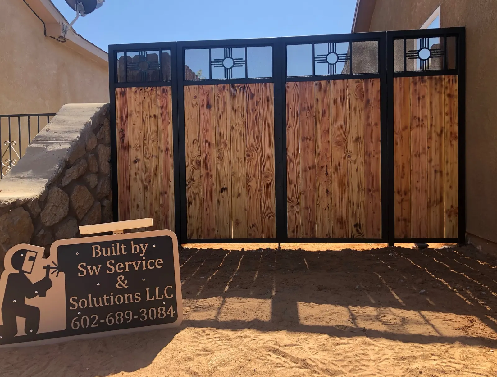 Wood-and-steel privacy screen with Zia sun windows and a Built by SW sign