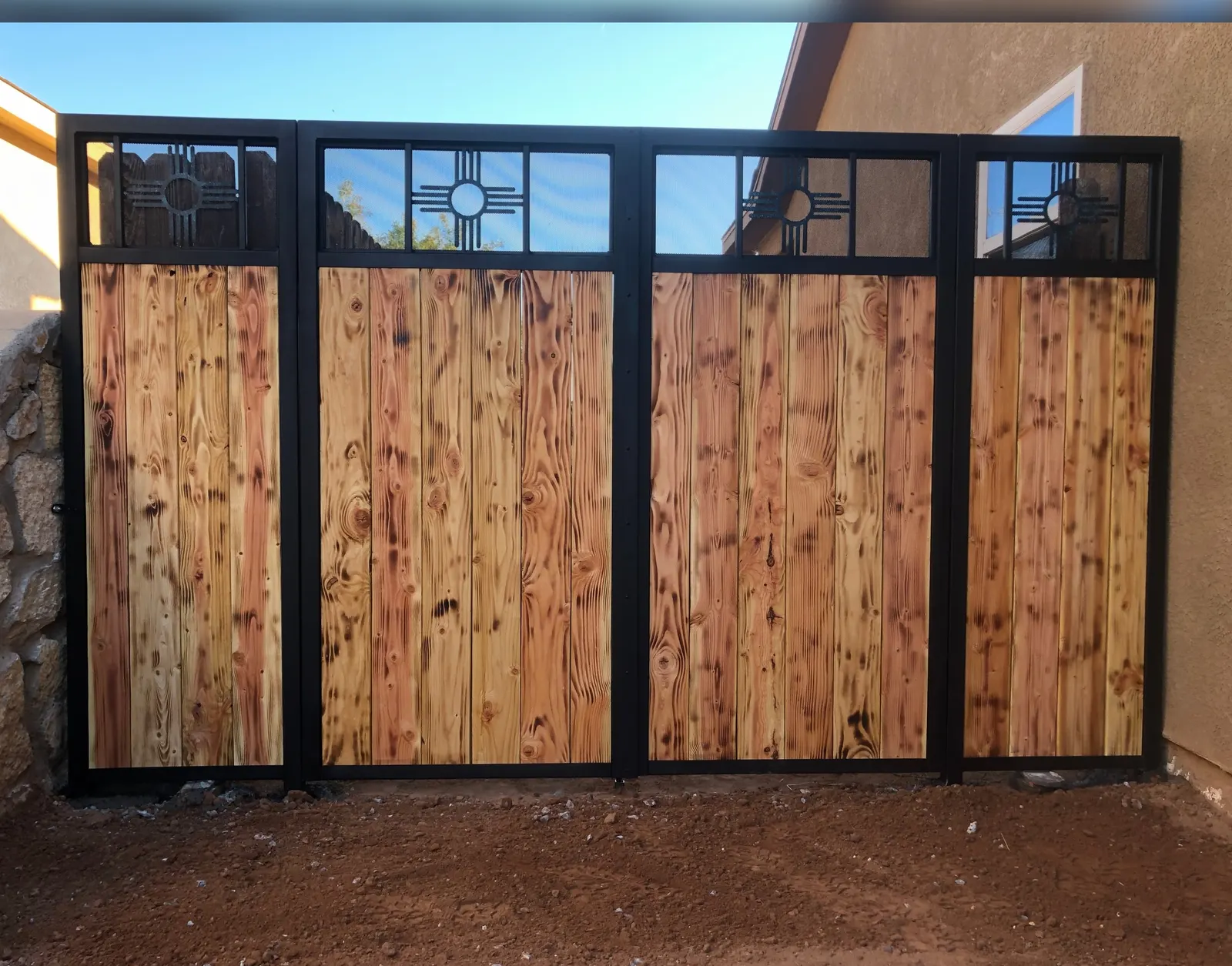 Four-panel wood and black steel privacy wall with Zia cutouts